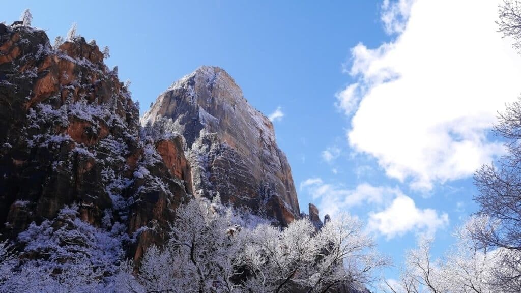 snowy cliff with cloud covering sun and blue sky in background