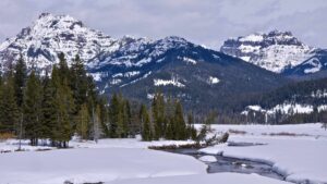 rivière gelée avec des montagnes enneigées et des pins