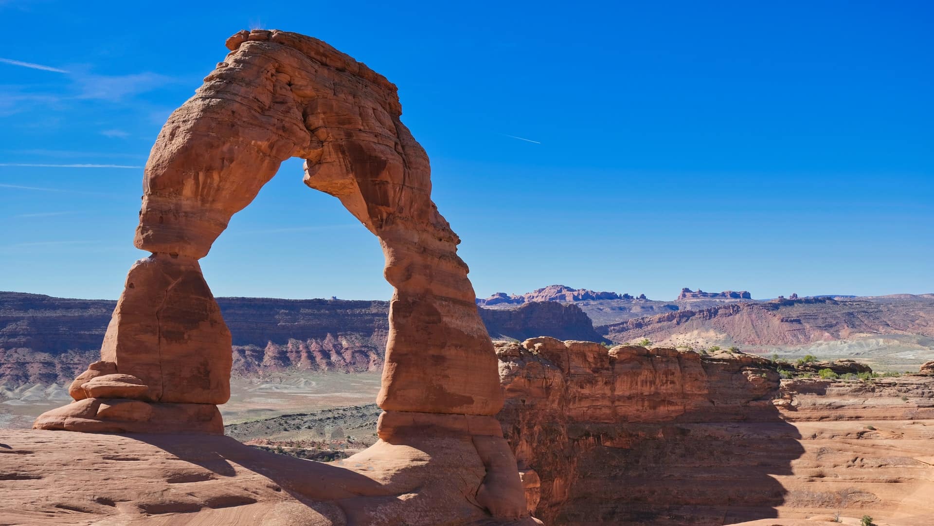 desert arch under blue sky above canyon